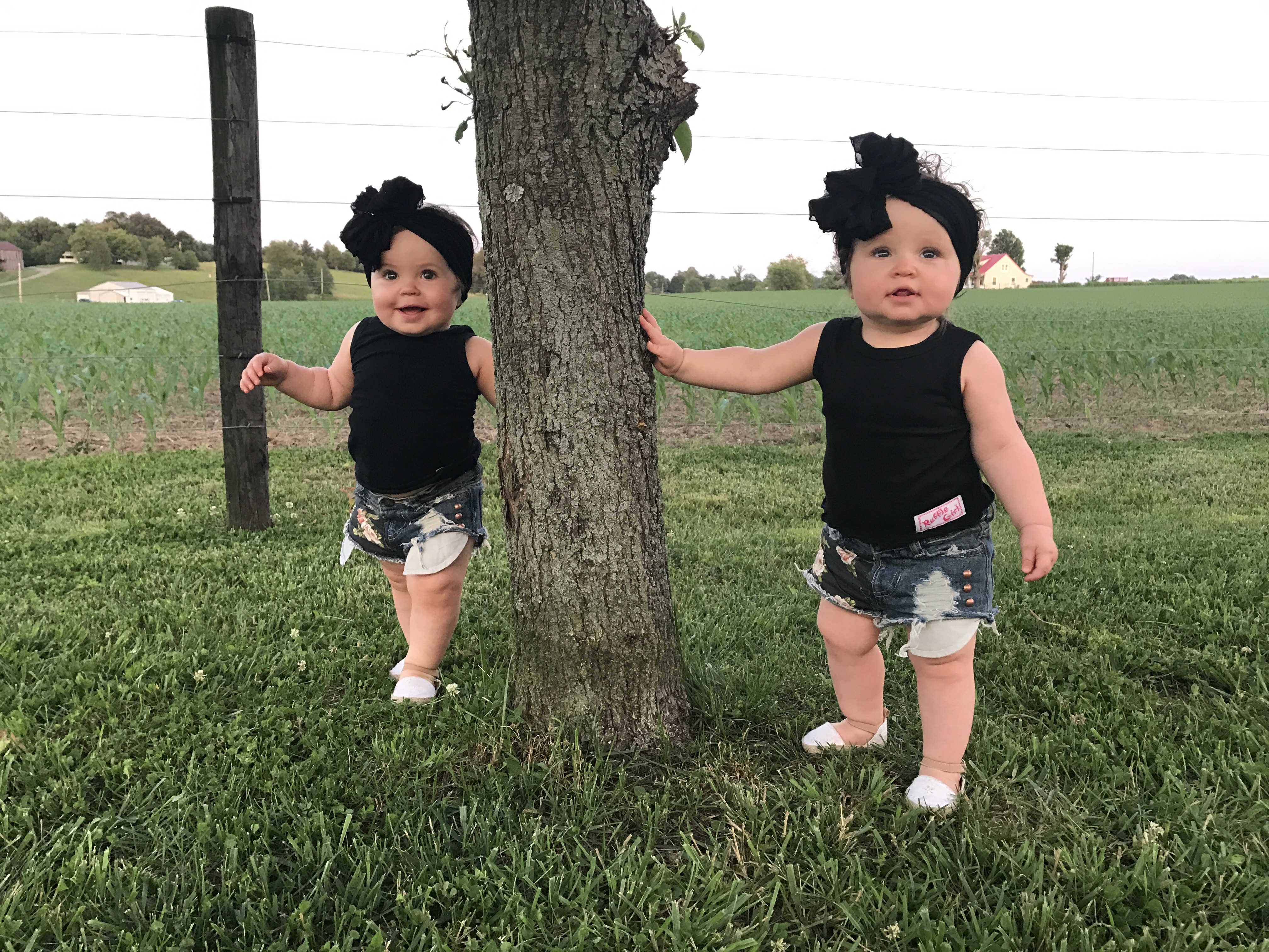 In love with this whole outfit! The ruffle bow headband and the distressed, denim shorts get all the heart eyes! The detailing on the shorts is too cute! These twin girls know how to ham it up! #twingirls #toddlerfashion #springfashion